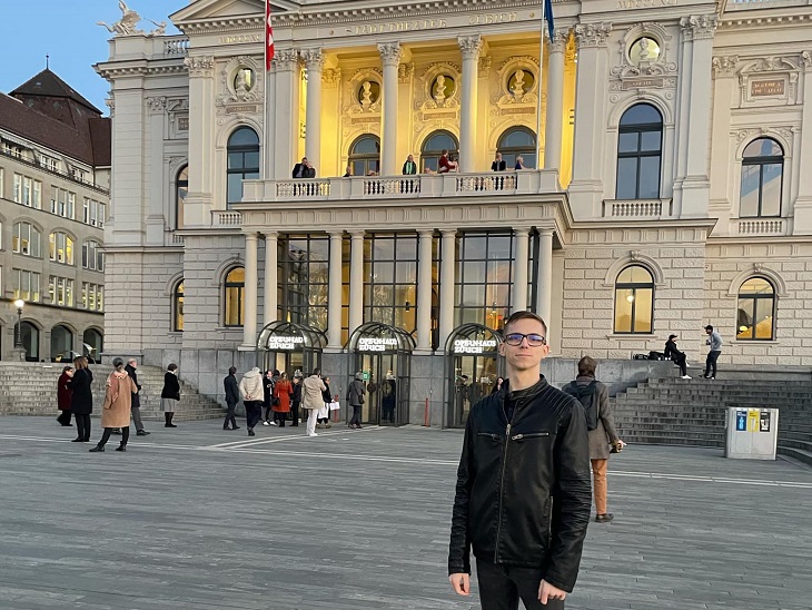 Fiatal férfi a Zürichi Városháza épülete előtt áll a téren
