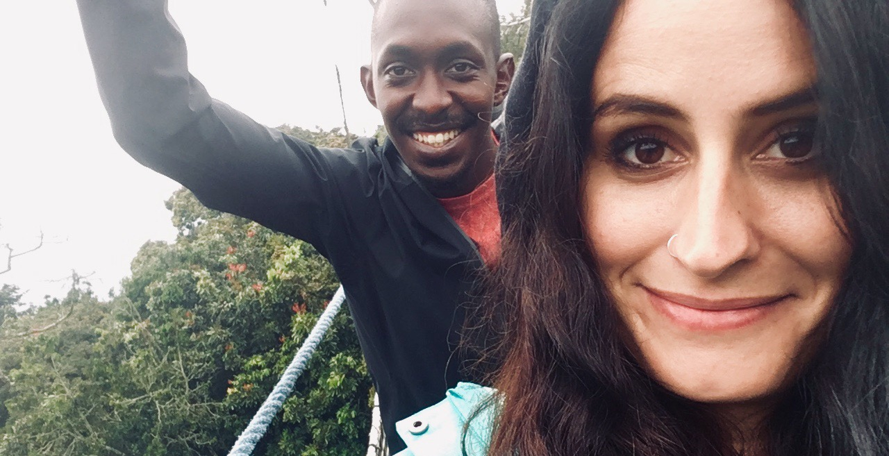 Ruandában a lombok között húzódó hegyi függőhídon egy helyi férfi és egy fiatal lány áll és néz a kamerába