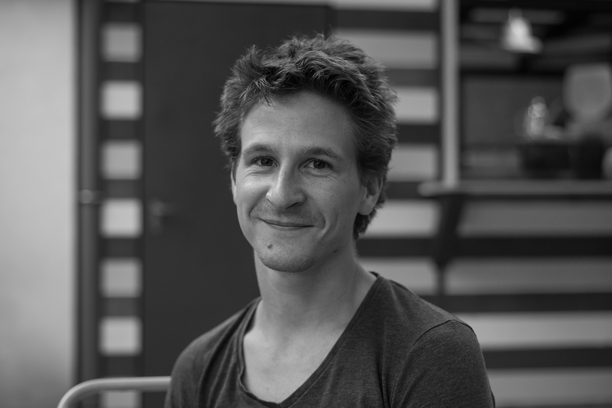 Szalai Dániel portéfotója egy fekete fehér képen mosolyog a kamerába egy fiatalember