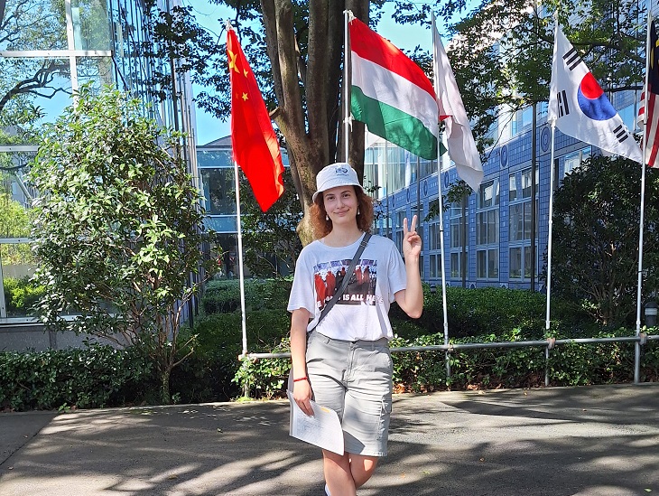 egyetemista lány halászsapkában a magyar és a japán zászló előtt
